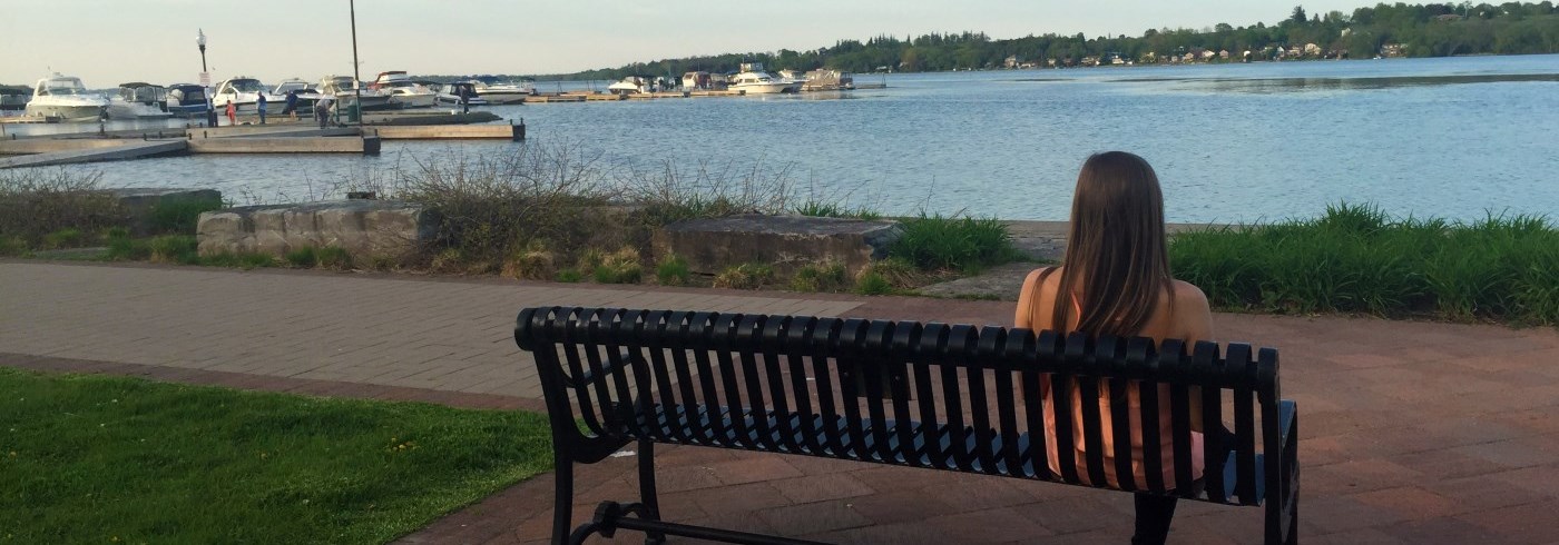 Woman sitting on a bench overlooking the Port Perry waterfront