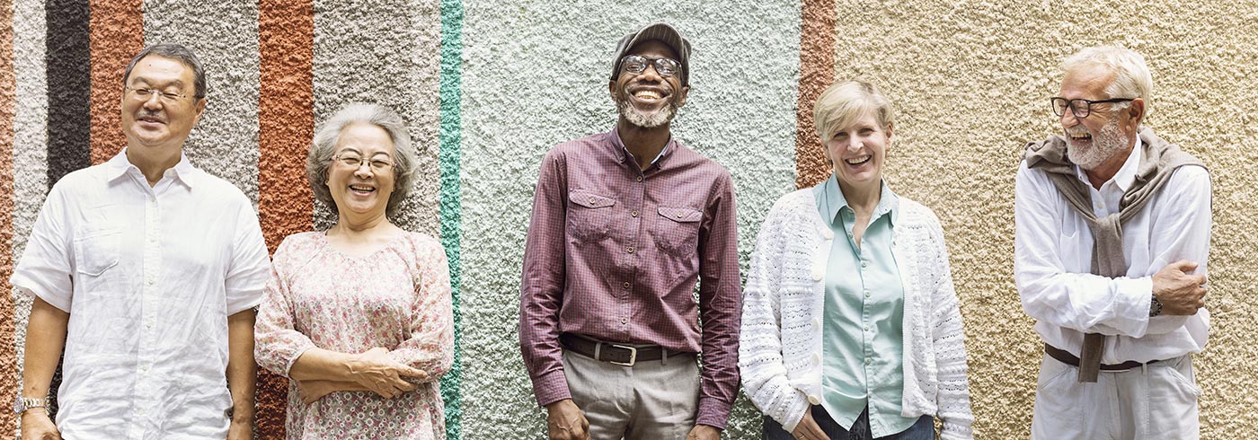 Group of older adults leaning against a wall.