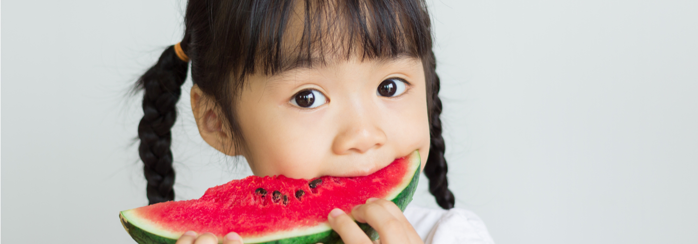 Young girl eating a slice of watermelon.