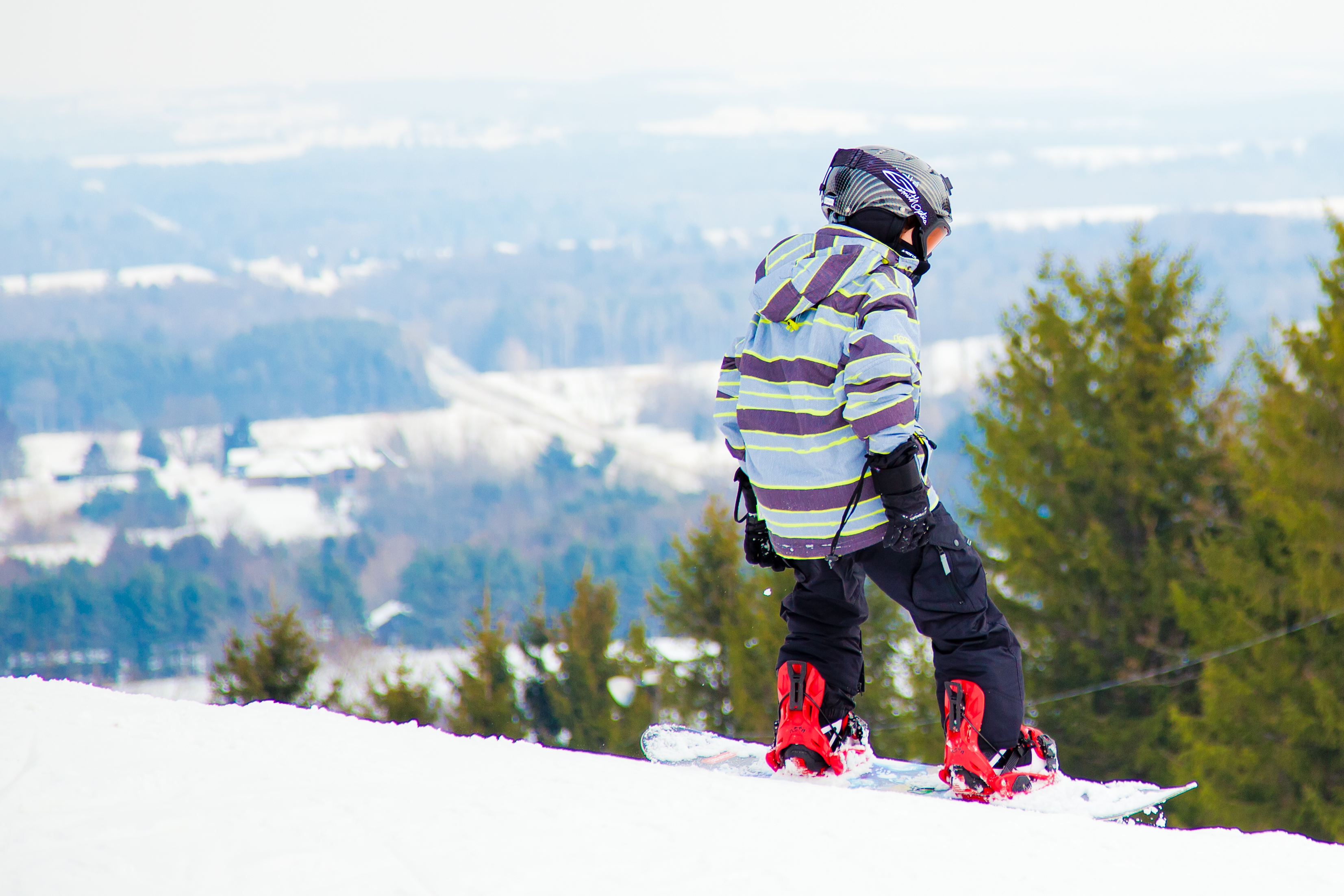 Snowboarder at the top of a ski hill with a view