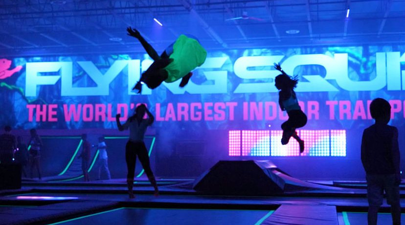 Kids jumping on trampoline under multi coloured lights