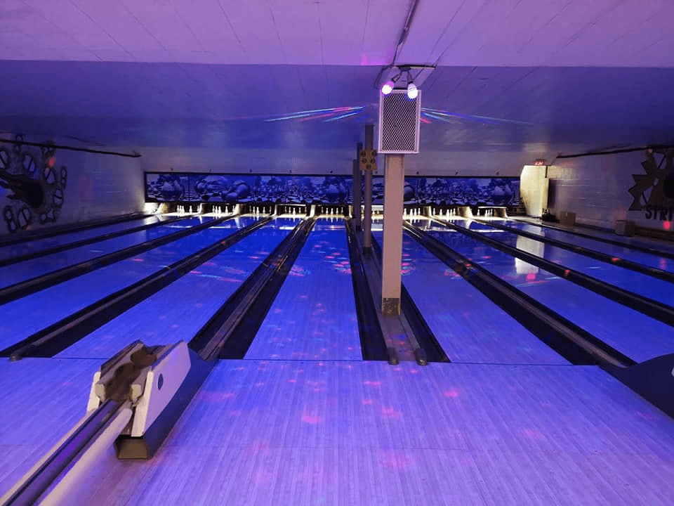 Empty bowling lanes lit by blue and purple lights