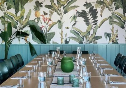 Chuuk Restaurant table in front of a wallpapered wall with greenery and birds. 