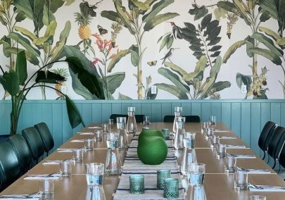 Chuuk Restaurant table in front of a wallpapered wall with greenery and birds.