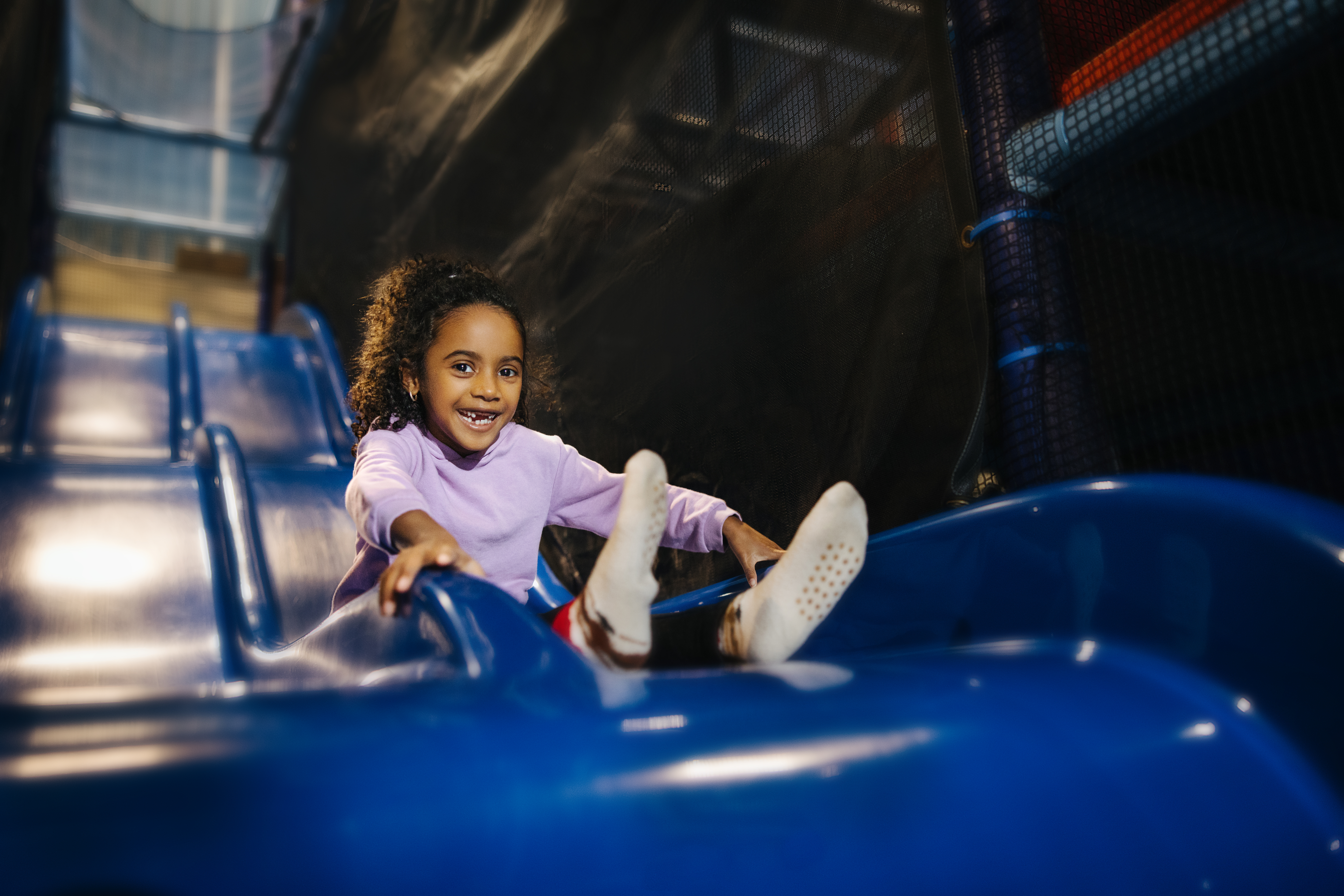 Little girl sliding down a blue slide