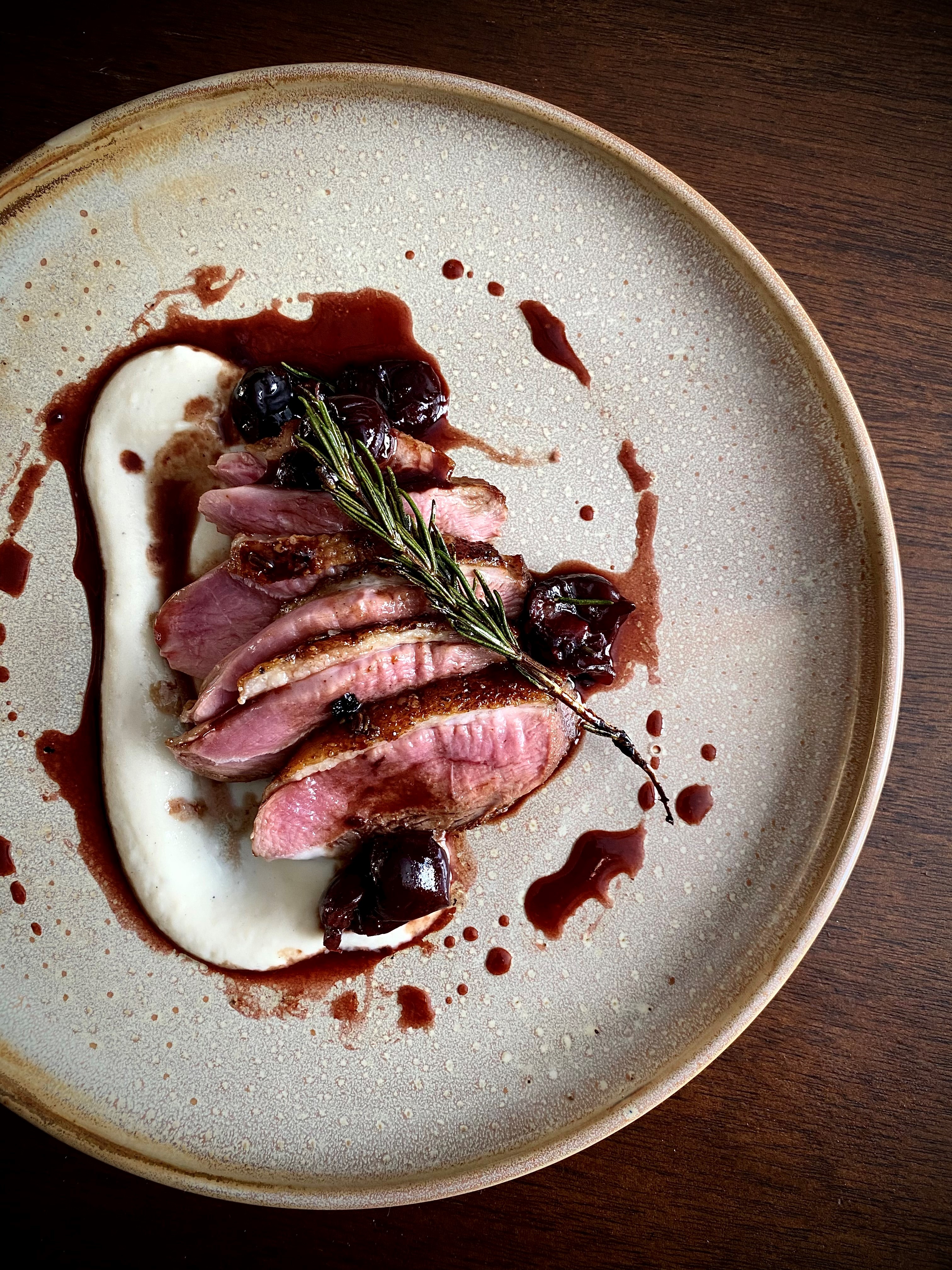 Lavender infused maple syrup glazed duck breast on a white plate