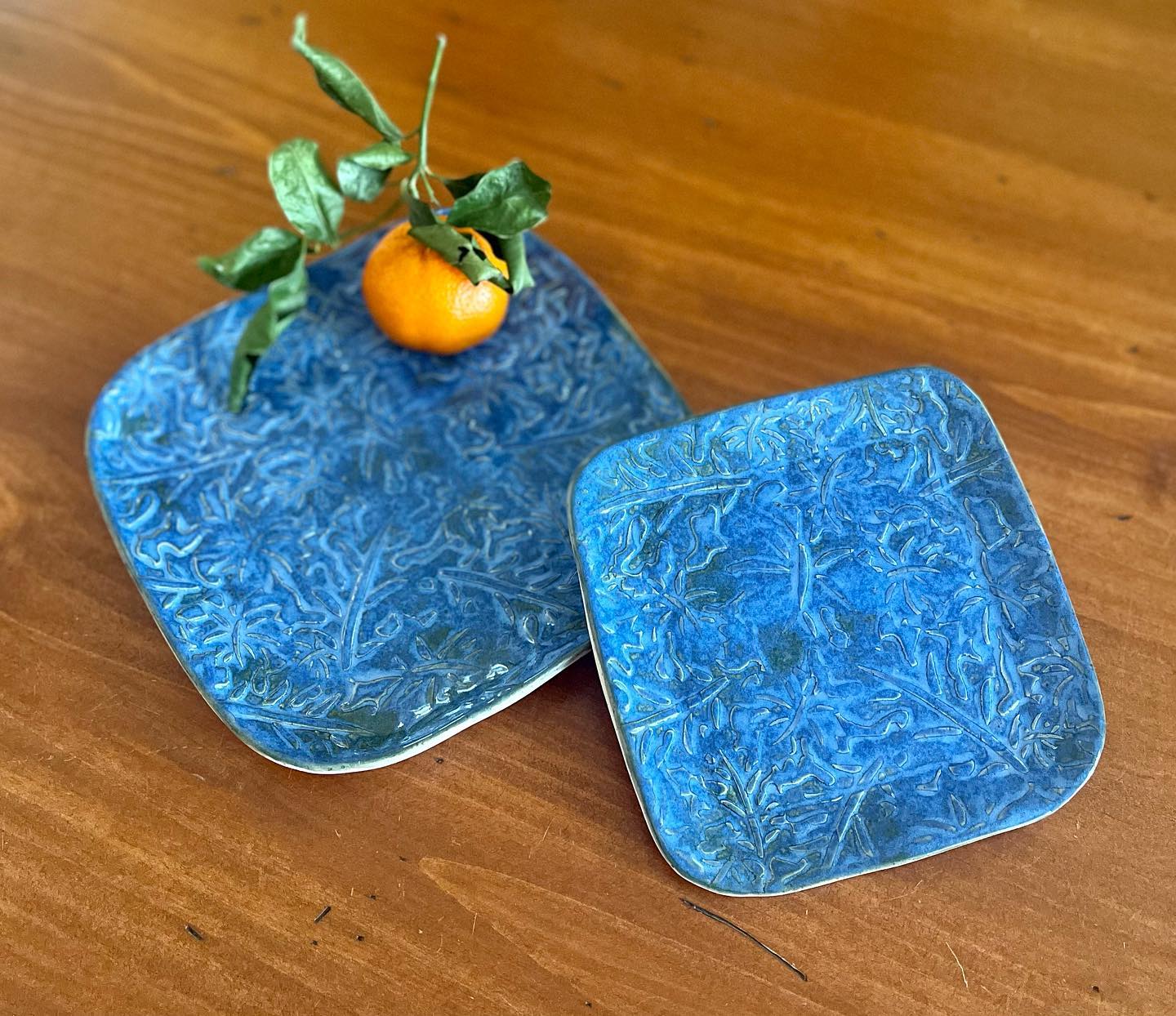 Blue plates with an orange from Greenmantle Pottery