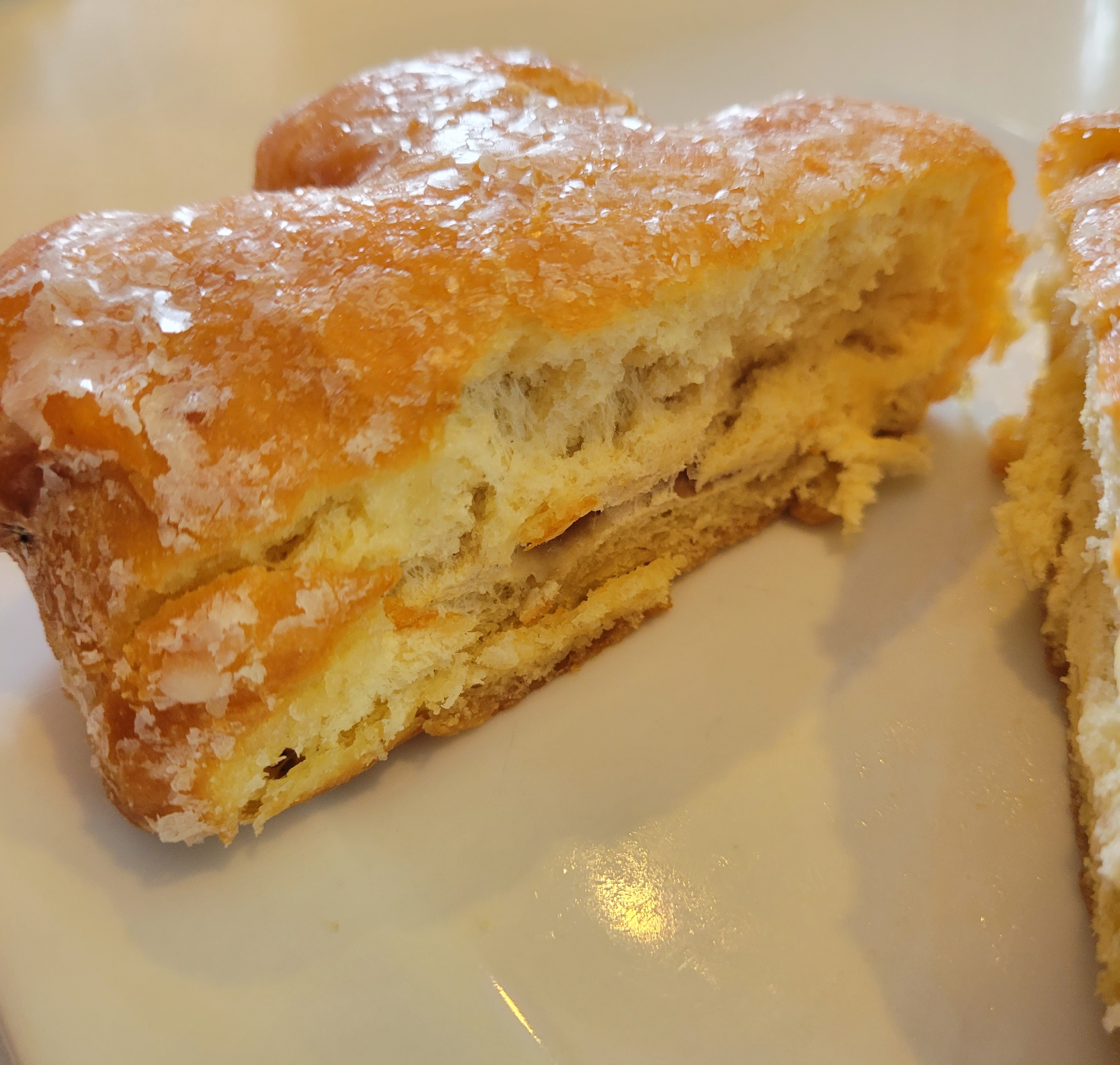 Hollywood Donuts apple fritter served on a white plate and cut in half