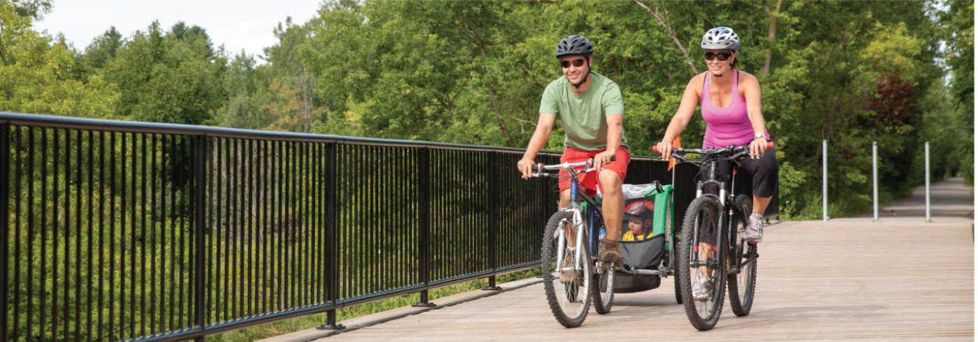 Man, Woman and Child riding bikes across a bridge in Durham Region