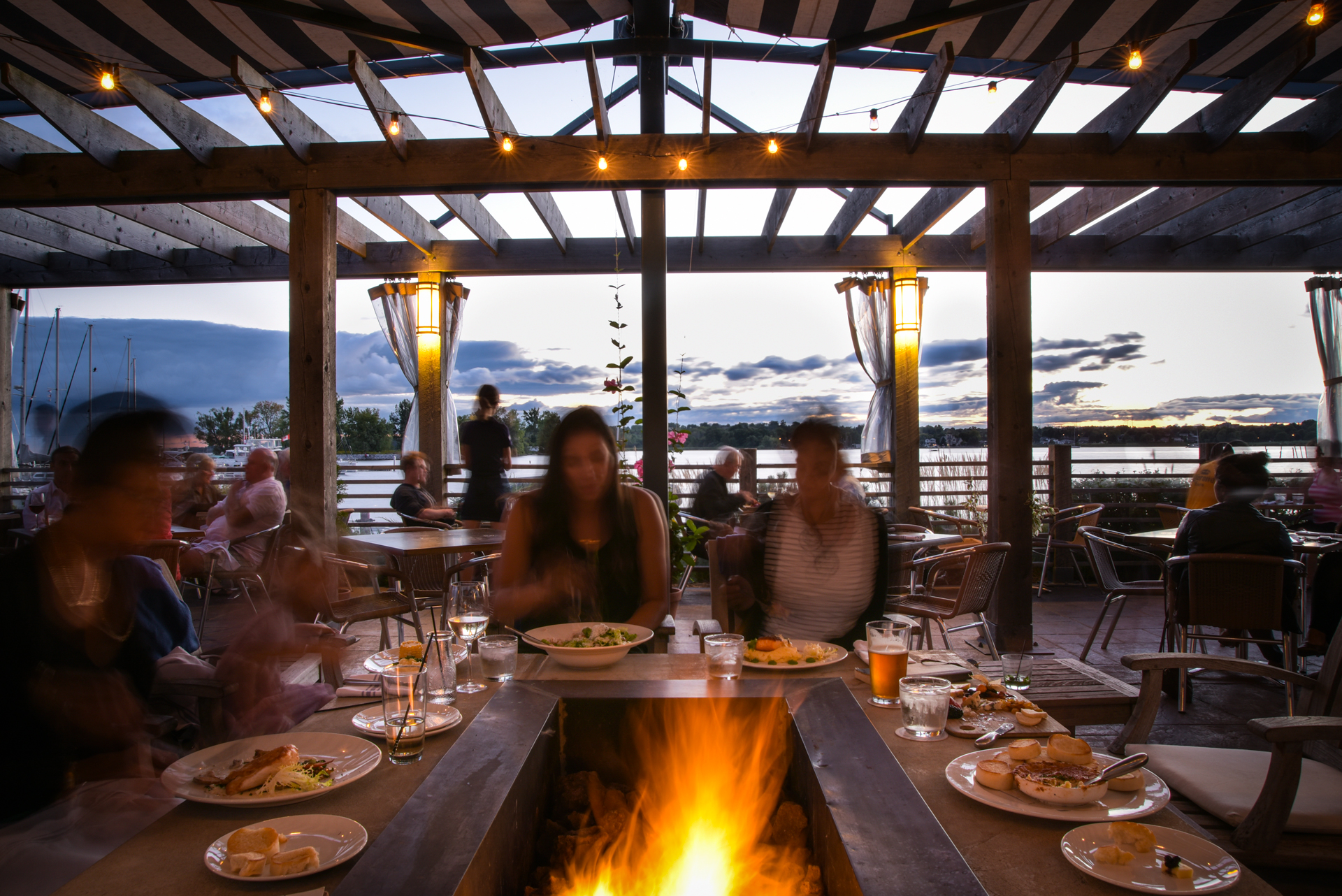 People eating around outdoor fireplace on patio