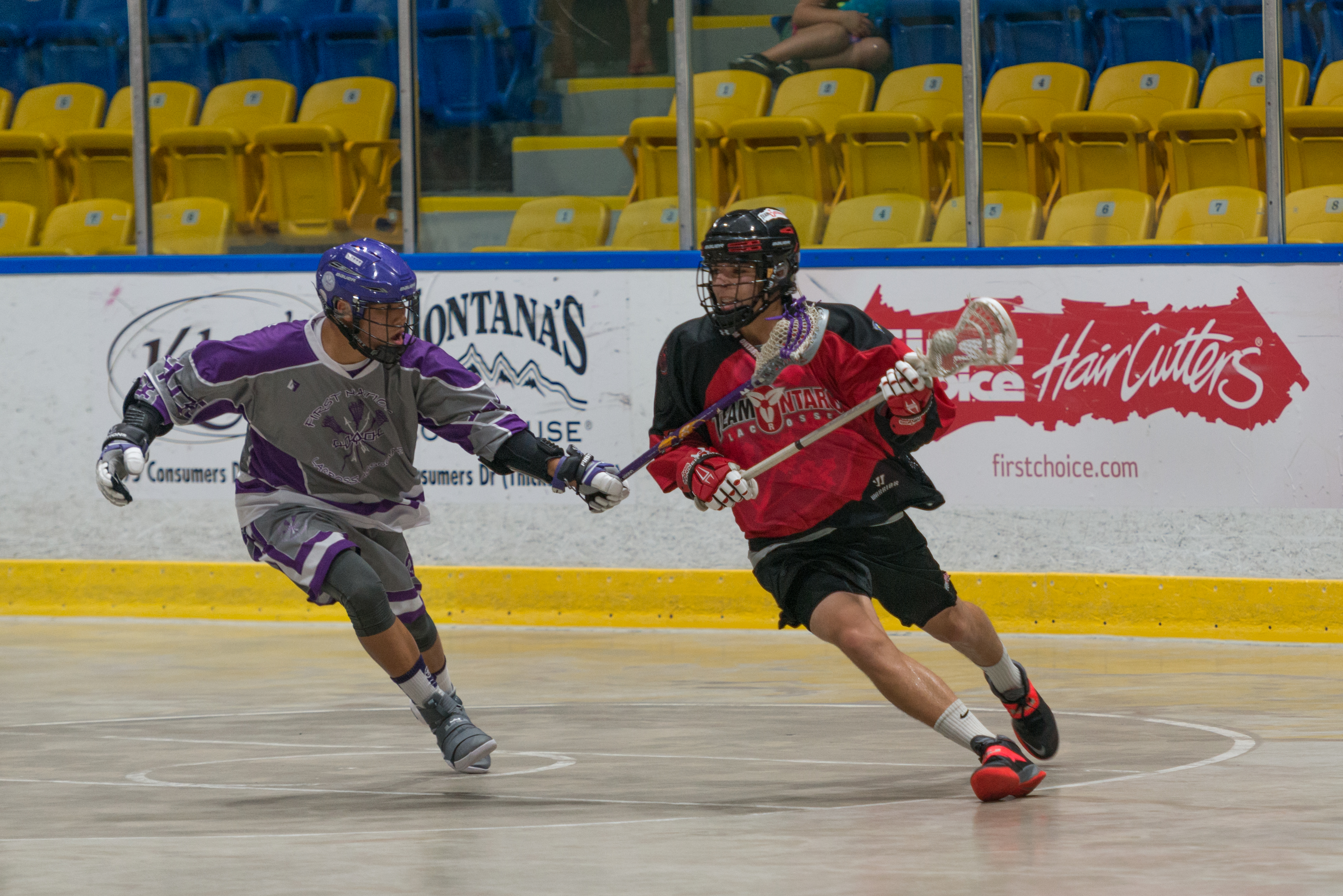 Two people playing lacrosse indoors