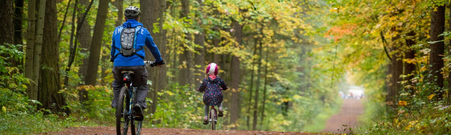 Adult and child mountain biking on trail