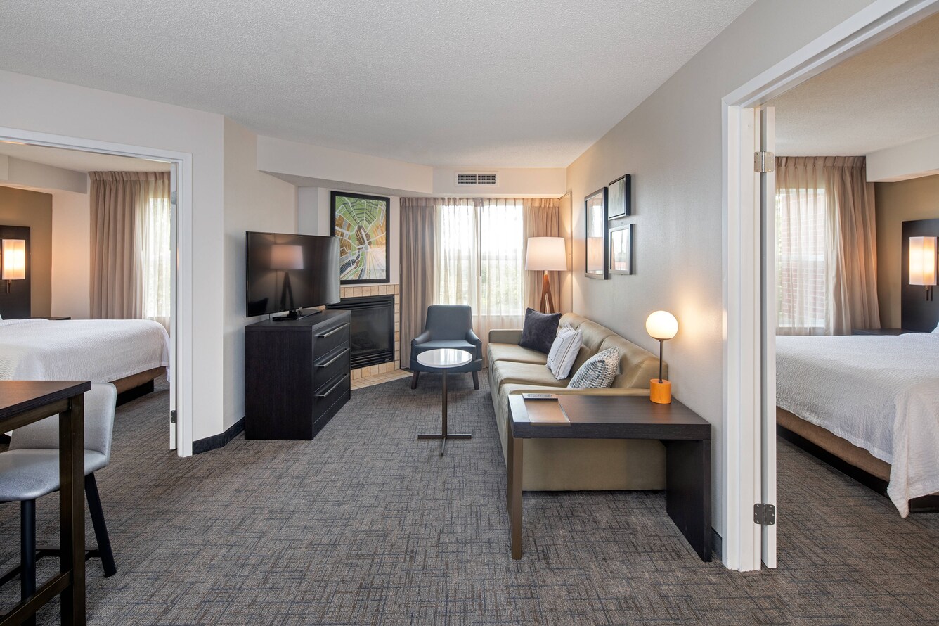 Residence Inn Whitby Hotel guest room with two bedrooms and living area with couch and TV