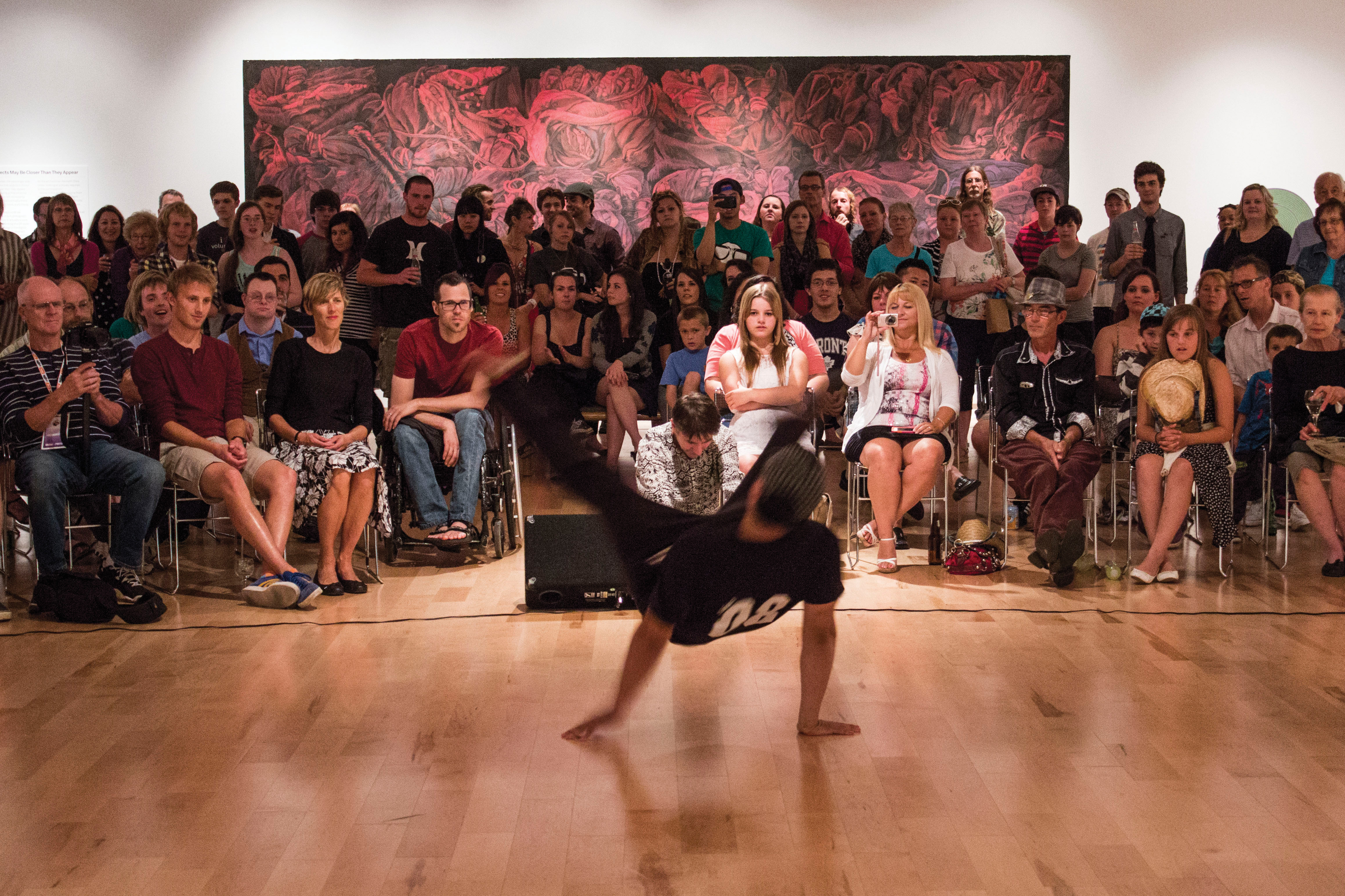 A crowd of people watching a break dancer inside the Robert McLaughlin Gallery
