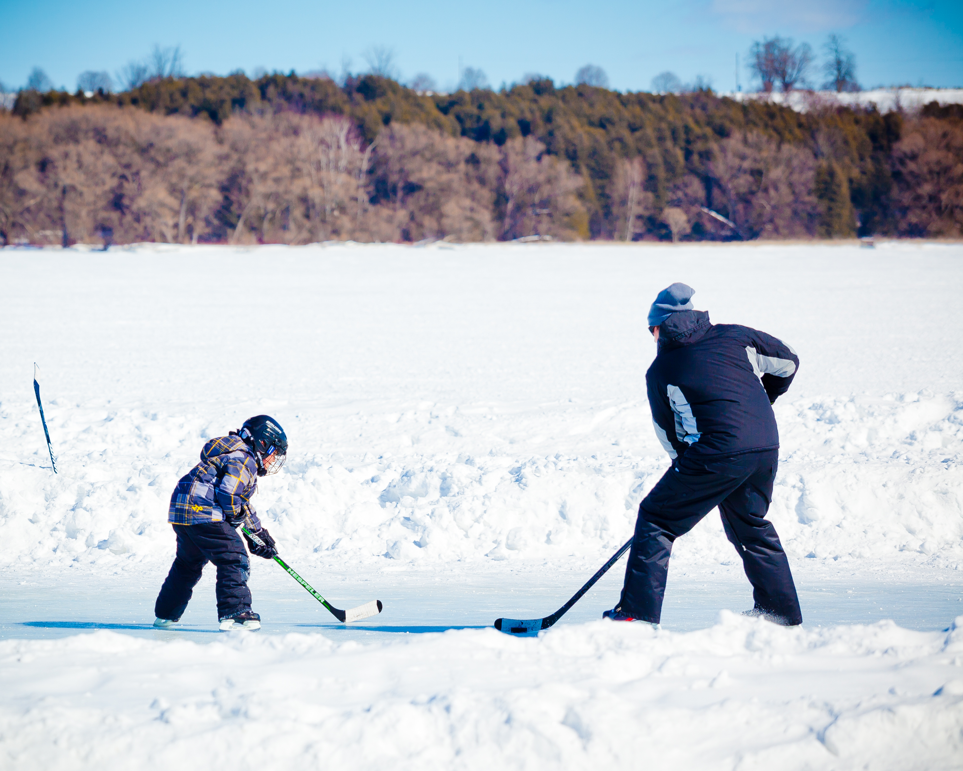 Man and child playing hockey on frozen lake