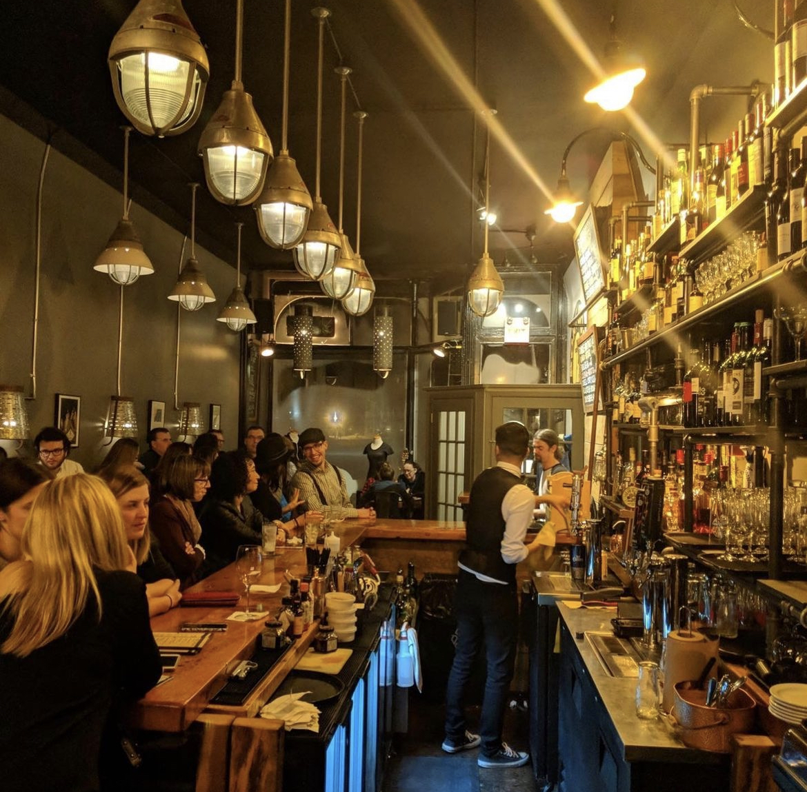 Bar area filled with patrons with soft yellow and gold lighting