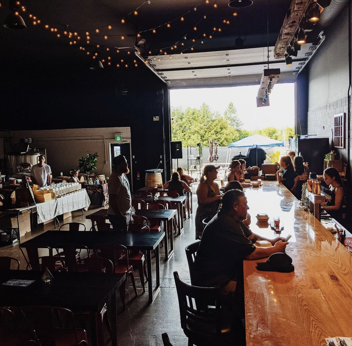 Patrons sitting at a long table inside Tilted Glass Brewing