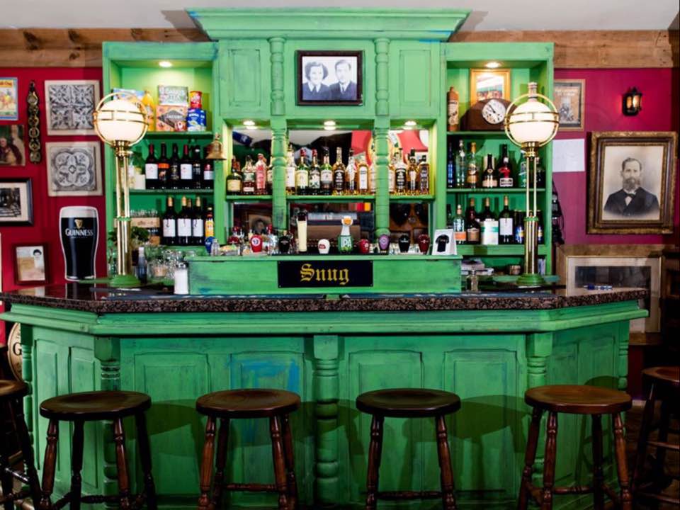 Green bar with stools and photos on the wall