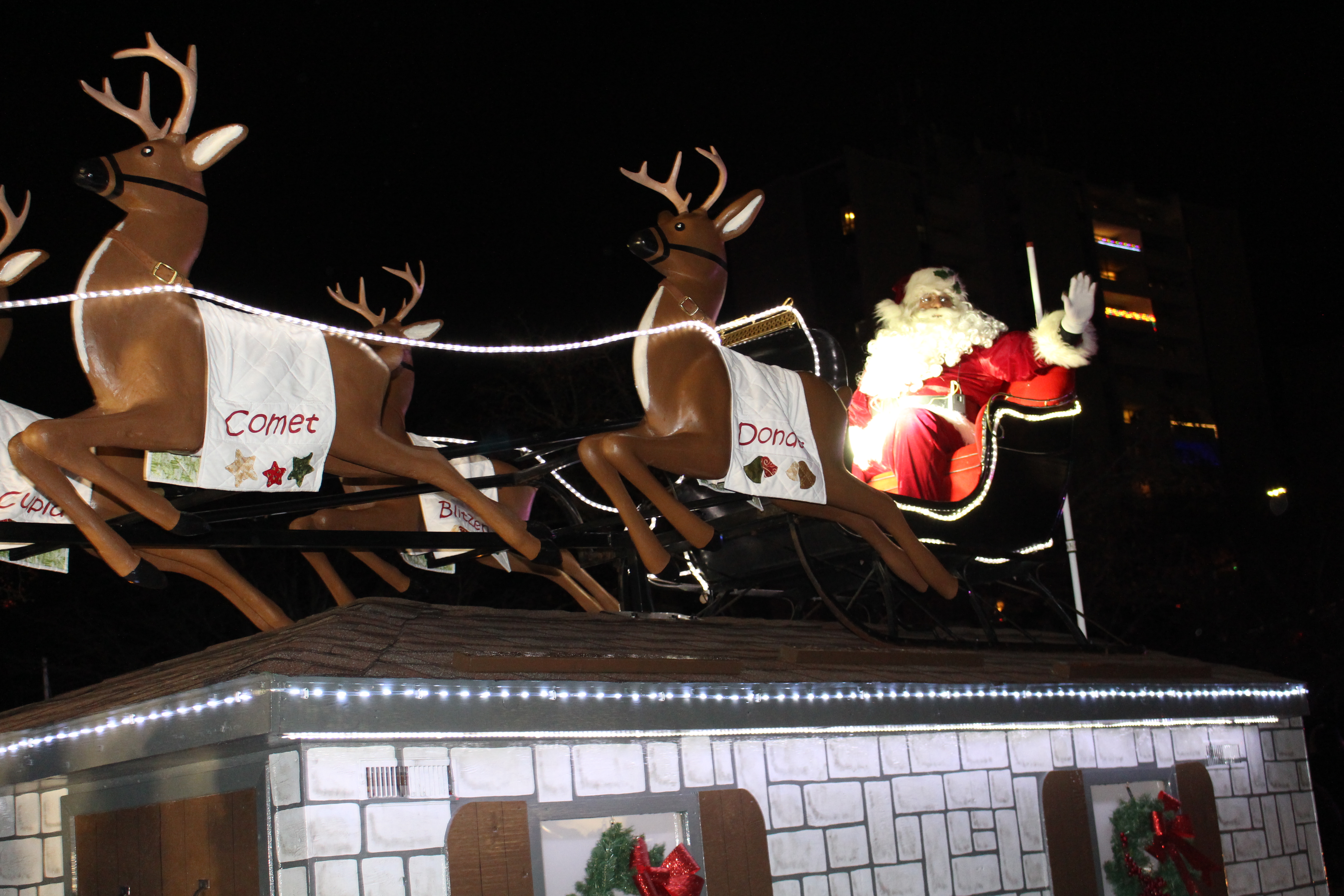 Santa in his slay with two reindeer on the roof of a house