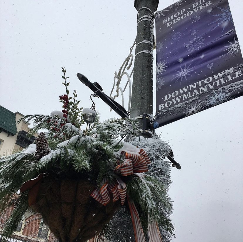 Lamp post with Downtown Bowmanville sign and greenery with snow