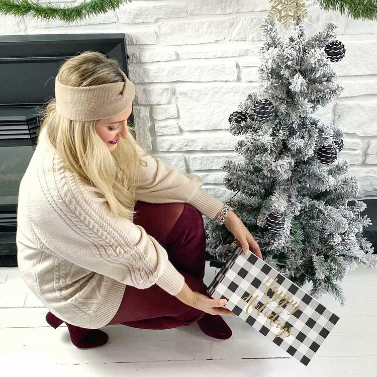 Woman looking at gift under a Christmas tree