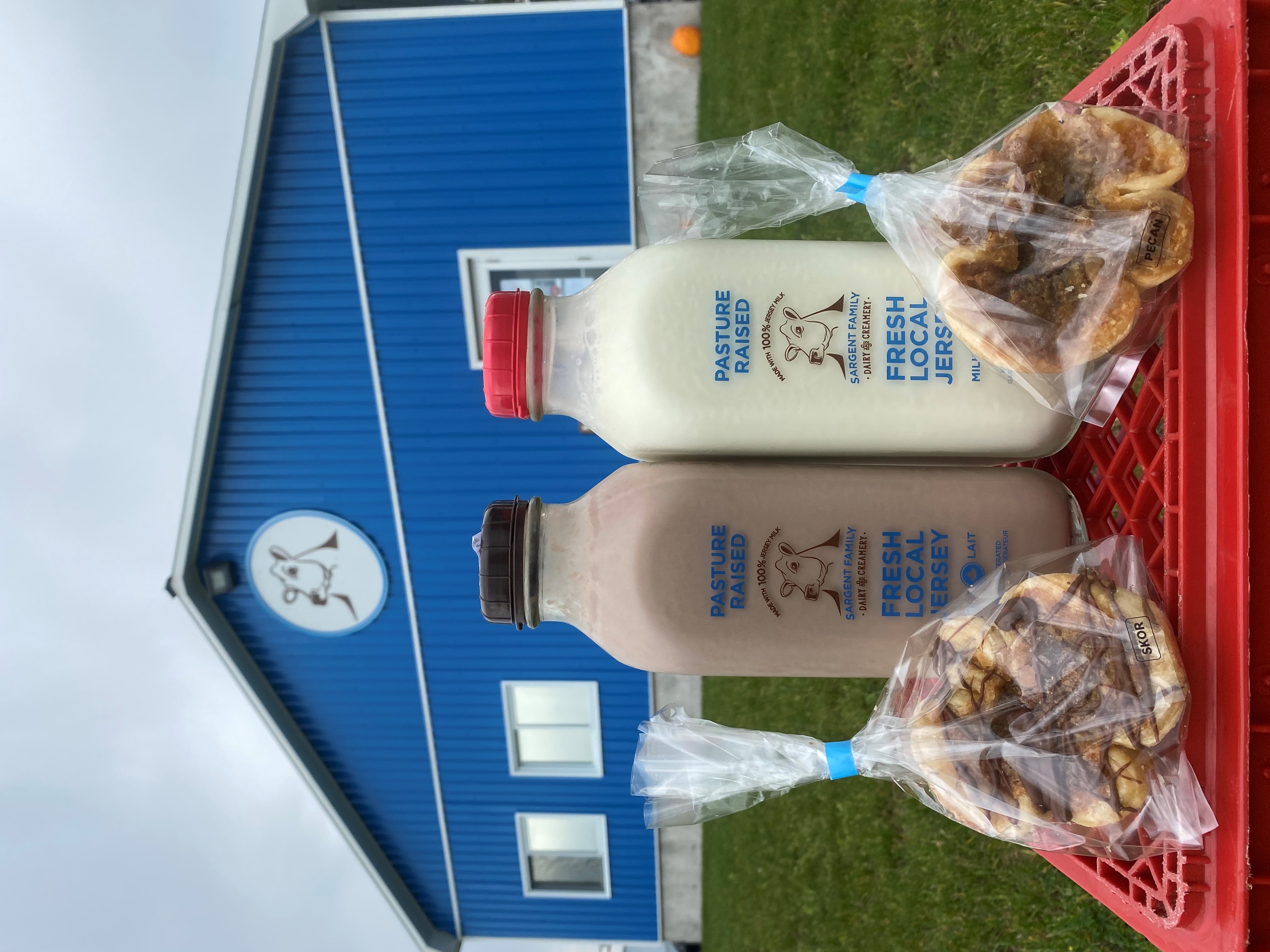 Milk bottles and baked goods in front of blue barn