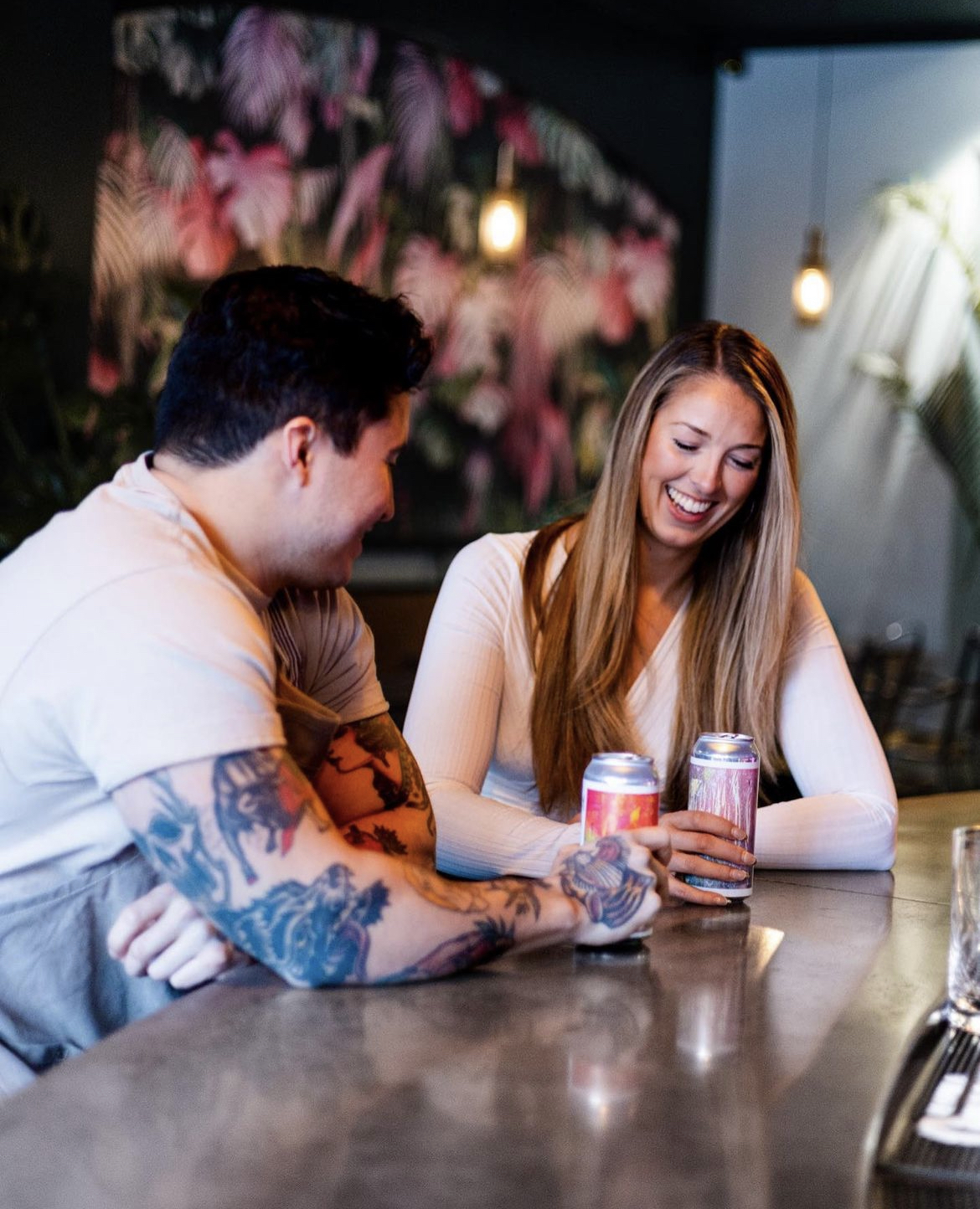Couple sitting at Surf Kitchen's bar with cans of beer