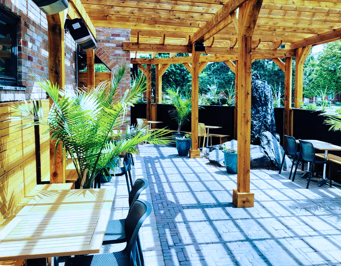 Patio tables, plants and a wooden roof at the Brock House