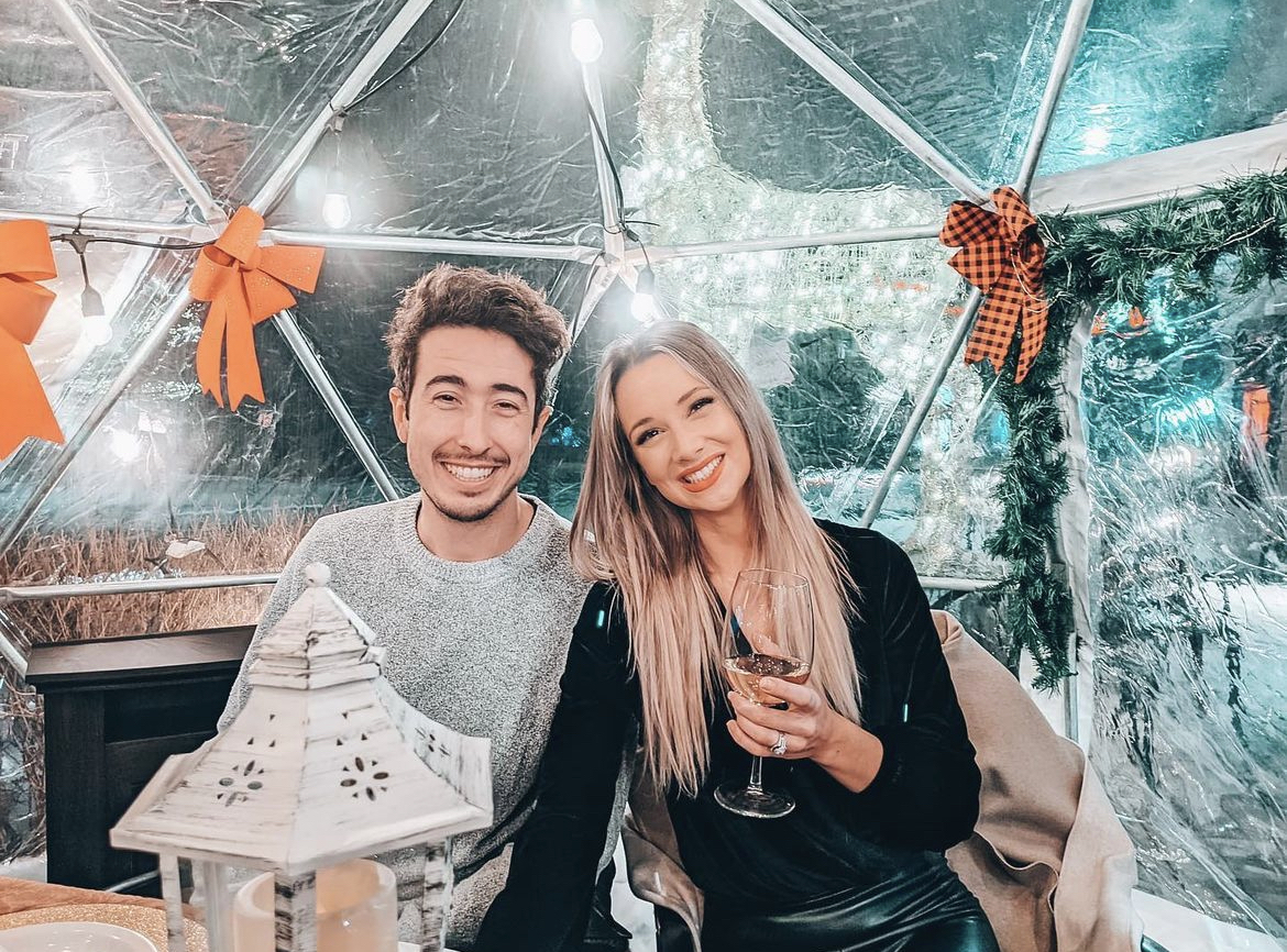 Two people dining in the dome with red bows, a fireplace and lantern decor