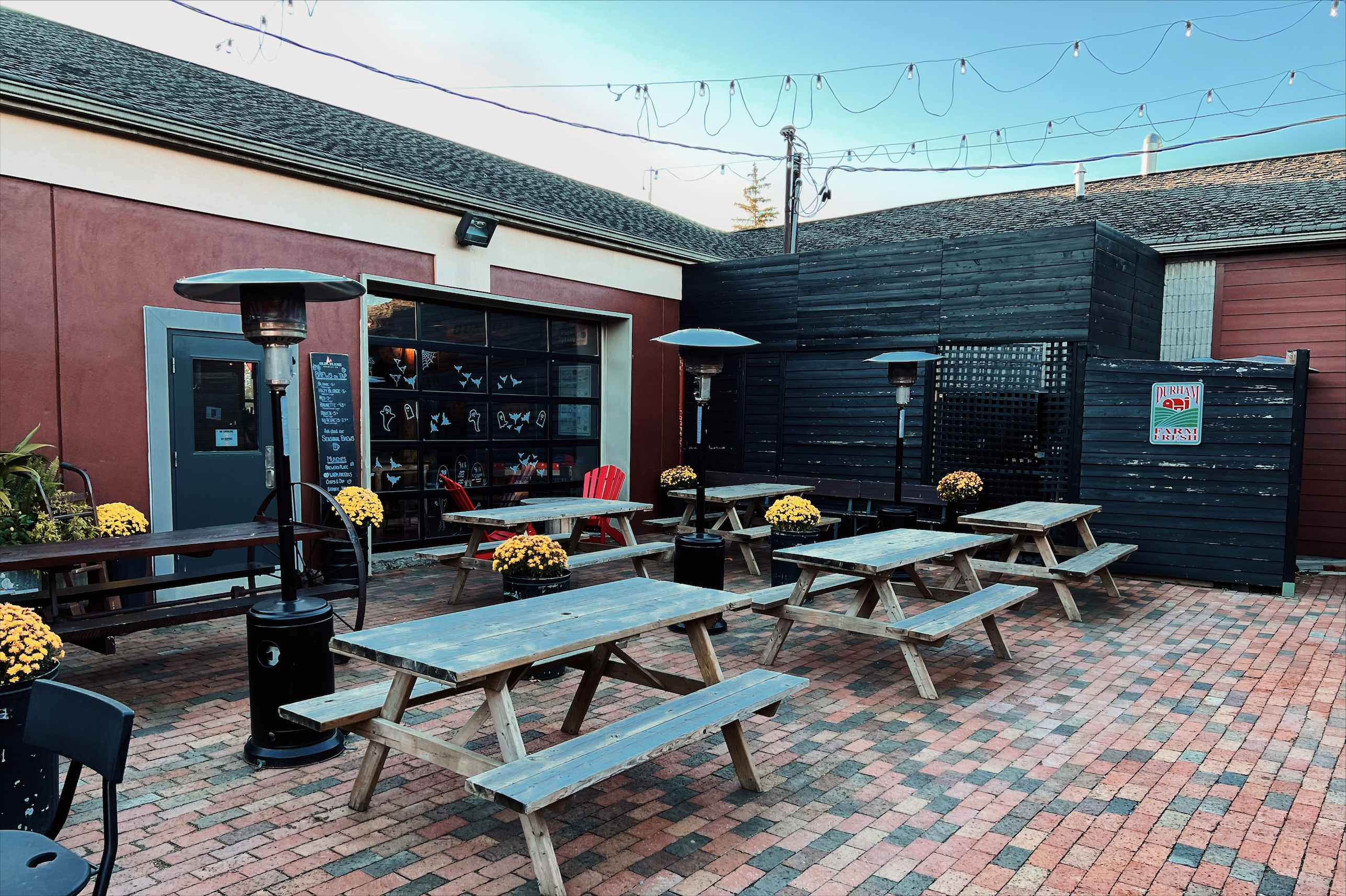 Outdoor patio with picnic tables and heaters at Old Flame Brewery