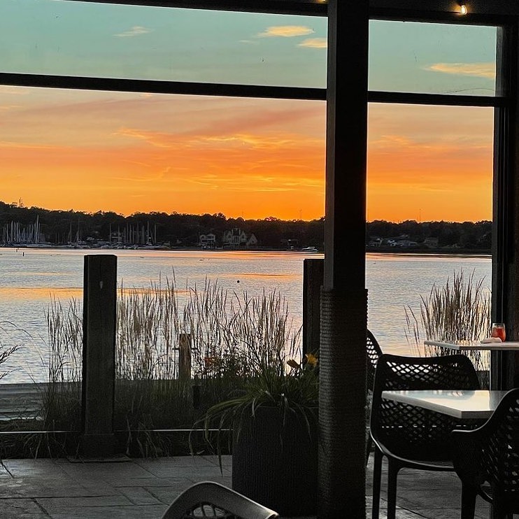 PORT Restaurant outdoor patio by the lake with an orange sky over the water