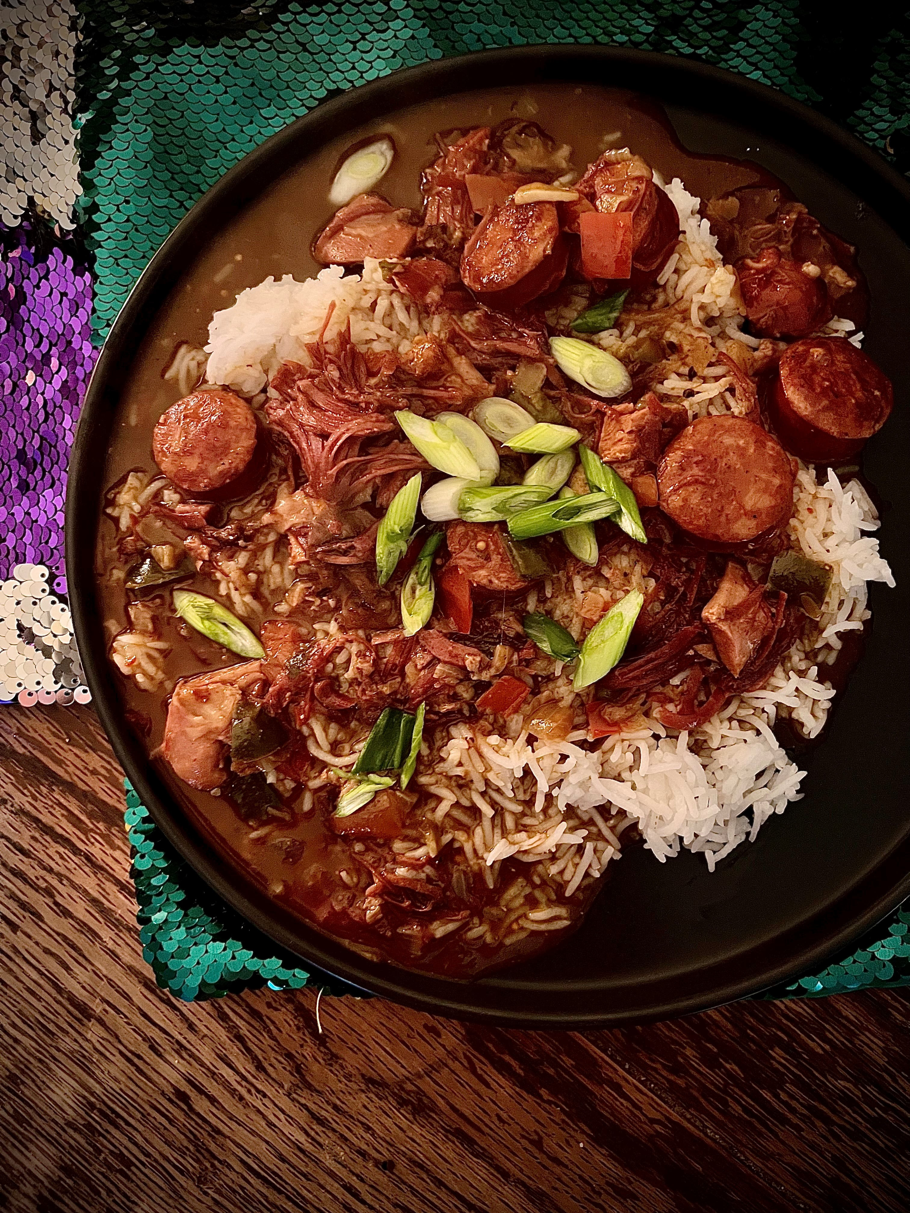 Smoked turkey and andouille gumbo in a skillet with green and purple placemats