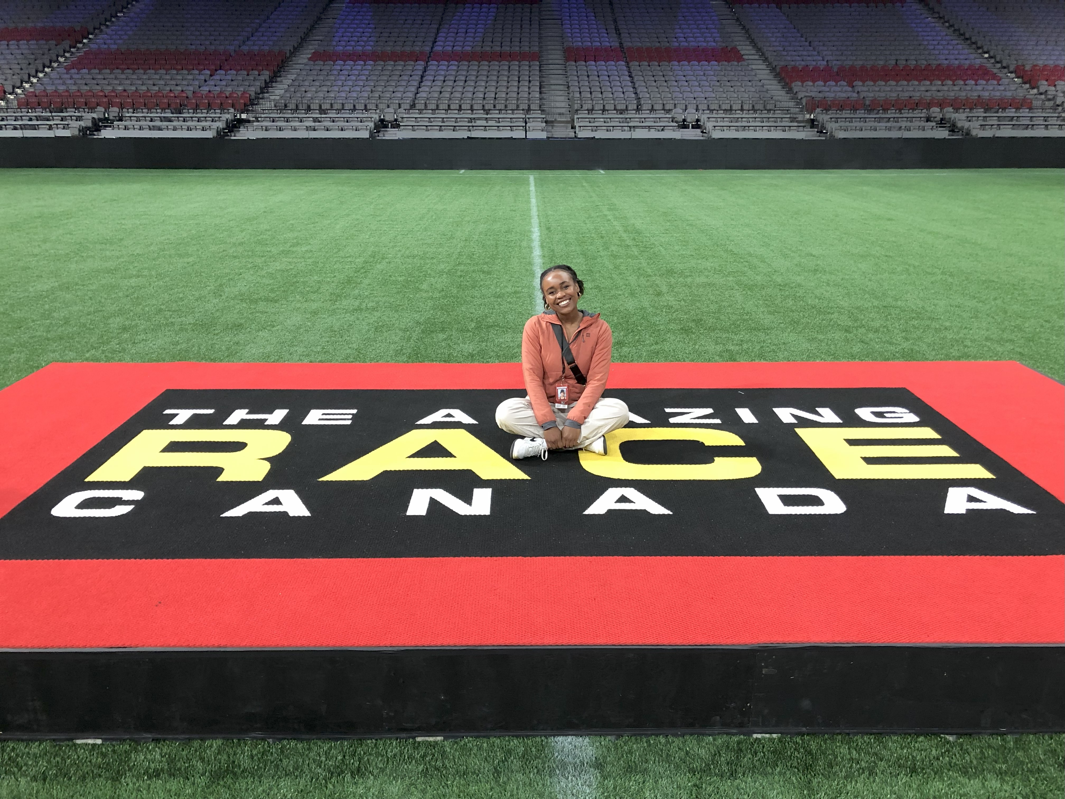 TV Producer and Director, Camille Lawrence, sitting in a stadium on top of a podium with text that reads, 