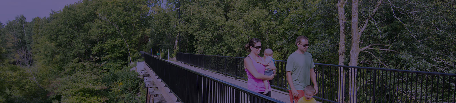 Family walking across a bridge in a forested area.