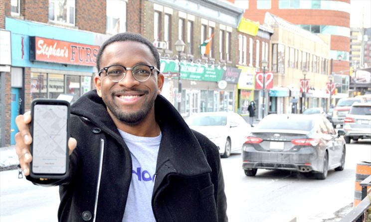 Hop In Technologies Co Founder, Boyd Reid, smiling with a smart phone showing their app in Durham Region, Ontario