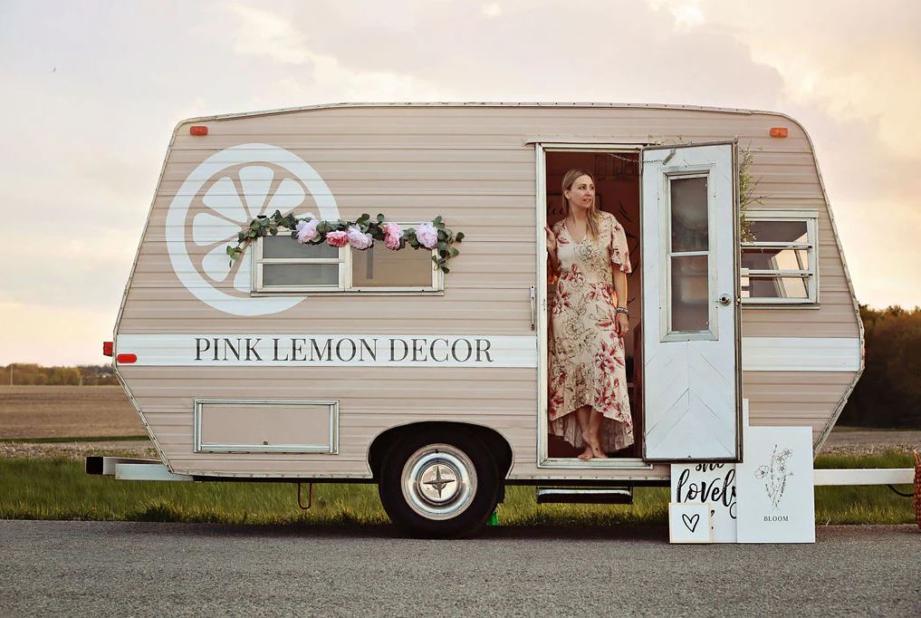 Pink Lemon Founder standing in the doorway of her branded vintage trailer.