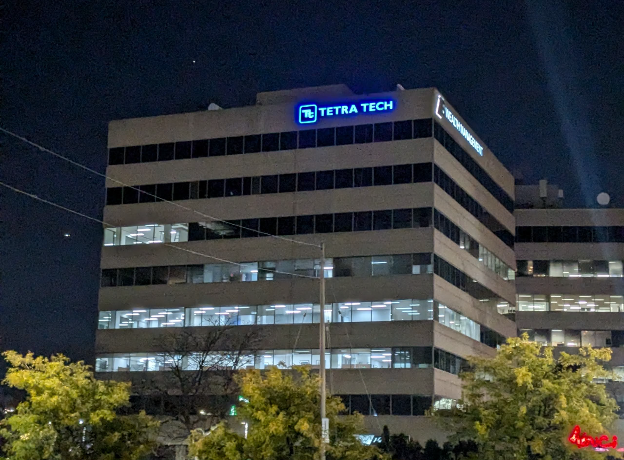 Tall building with Tetra Tech sign in Pickering at night.