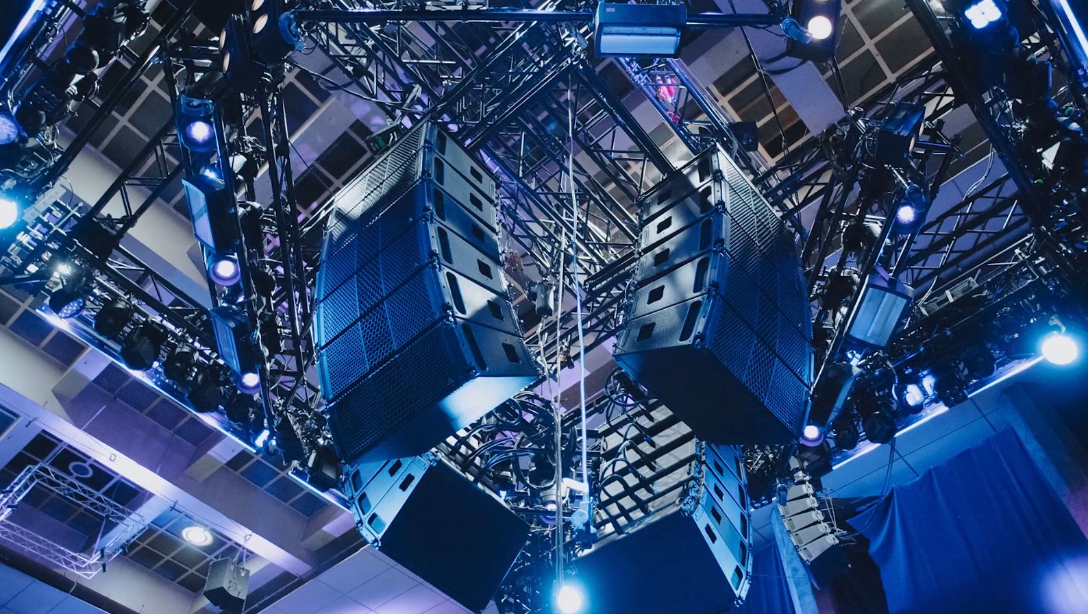 Speakers hanging from the ceiling at a venue.