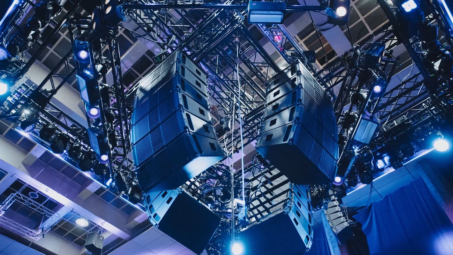Speakers hanging from the ceiling at a venue.