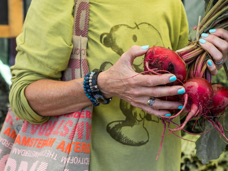 Beets in a shopper's hands at a farmers' market.