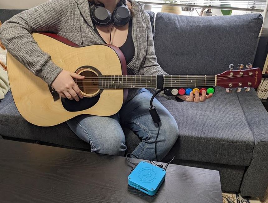 Person playing an guitar designed by Inclusive Instruments.