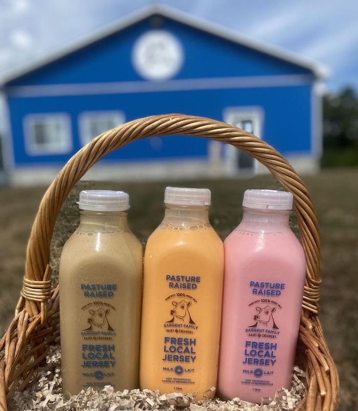 Bottles of chocolate, orange creamsicle, and strawberry milk in a basket.