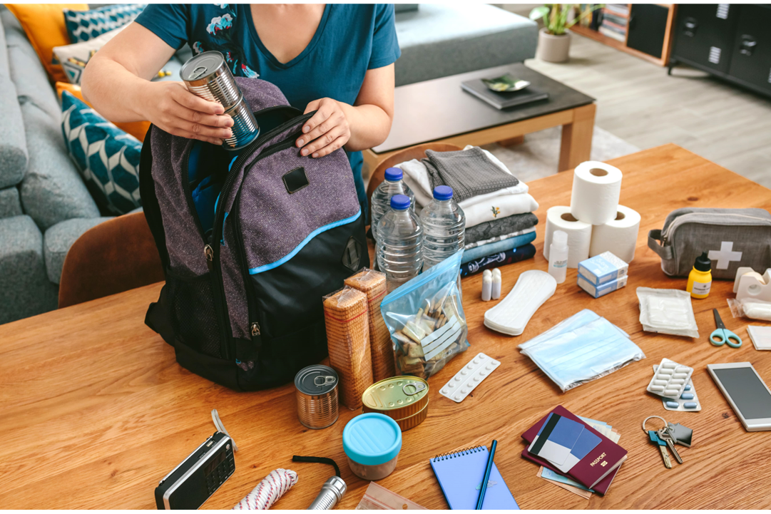 A woman packing a backpack with essentials for emergency