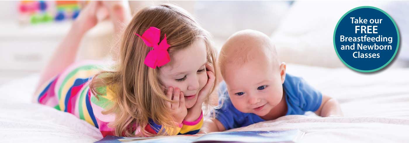 Toddler and baby looking at a book together