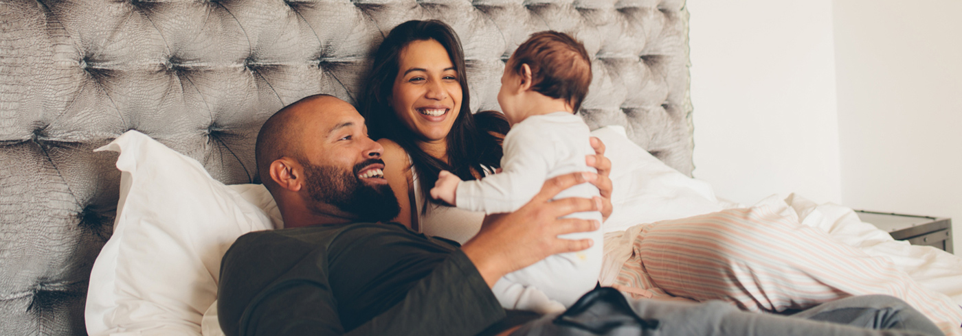 Couple interacting with new baby at home.