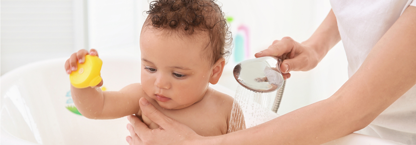 Mother safely bathing her child in the bathtub.