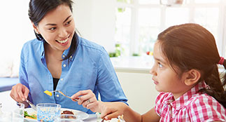 Mother and daughter eating at the table.