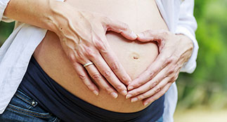 A woman holding her pregnant belly.