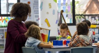 early childhood educator sitting at table full of children in a child care centre
