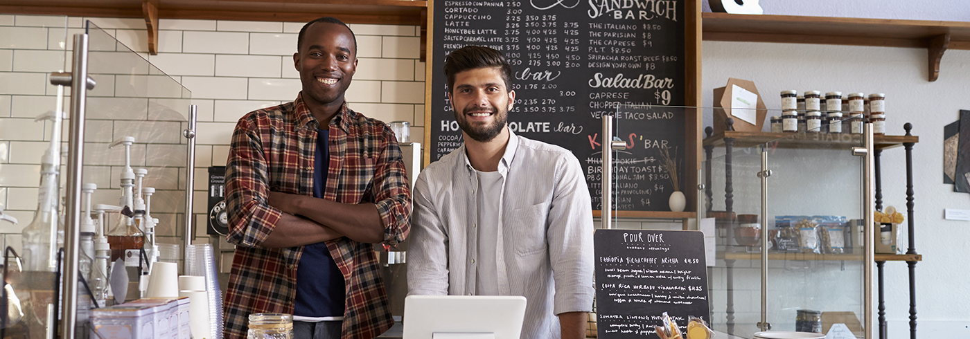 Staff smiling behind food premise counter.